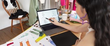 Beautiful asian Fashion designer drawing sketches for new collection on computer laptop. Designer creative workshop studio.