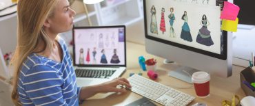 Side view of young Caucasian young female fashion designer using graphic tablet while working at desk in a modern office
